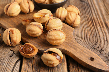 Cutting board with sweet walnut shaped cookies with boiled condensed milk on wooden background