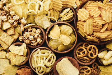 Colorful mix of salty snacks for beer varieties: chips and pretzels, onion rings and crackers. Non-healthy junk food background