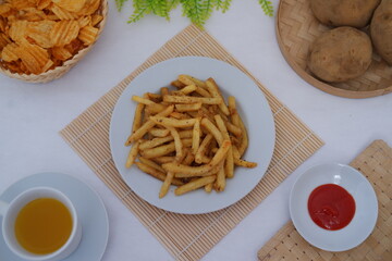 crispy French fries is served with a side of red dipping sauce on a bamboo mat