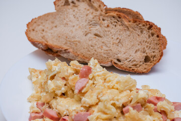 Plate of scrambled eggs with sausage and bread