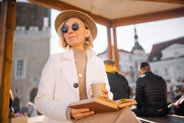 Woman enjoying a book and coffee in a cozy outdoor setting at a town square