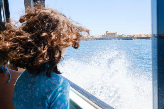 Anonymous person next to boat window with views of sea and island