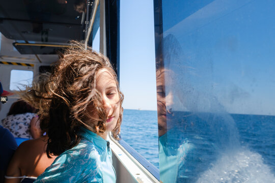 Kid posing next to boat window with views of Mediterranean Sea