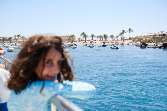 Kid on boat deck approaching Mediterranean island