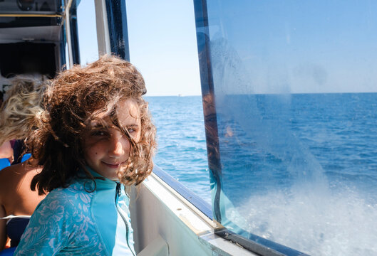 Kid posing next to boat window with views of Mediterranean Sea