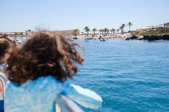 Kid on boat deck approaching Mediterranean island