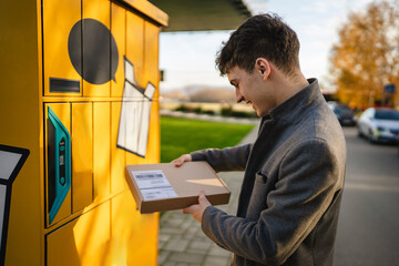 young adult man pick up the package on parcel machine on the street