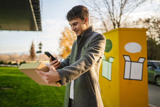 young man scan qr code on package with smart phone after receiving