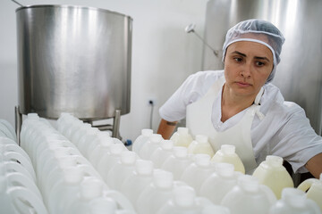 Female worker inspecting production line of milk bottles