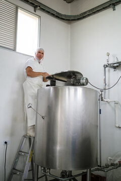Cheese factory worker preparing large pasteurization tank