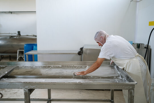 Factory worker cleaning equipment after work