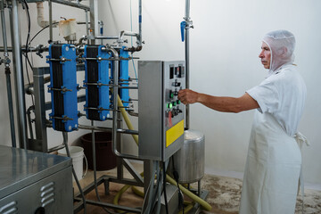 Factory worker operating equipment pushing button on control panel