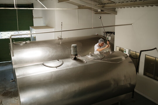 Dairy company worker measuring milk tank