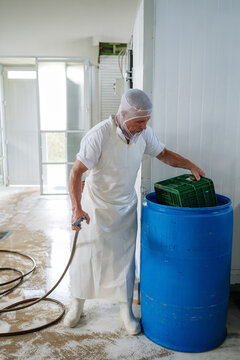 Cheese factory worker washing equipment after work