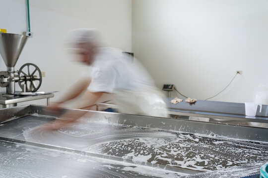 Food factory worker cleaning stainless steel table after work