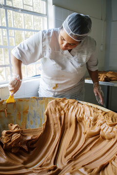 Latin american woman making dulce de leche in big container