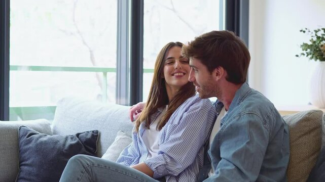 One dream for two of us. Romantic millennial spouses relax on couch together looking aside imagining happy future life. Young man and woman in love cuddling indoors creating plans on weekend vacation
