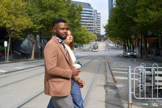 A professional couple cross Collins St Melbourne during work break 