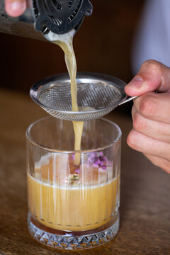 Bartender preparing whiskey sour cocktail using strainer