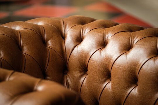 Close-up of tufted brown leather sofa texture in warm light