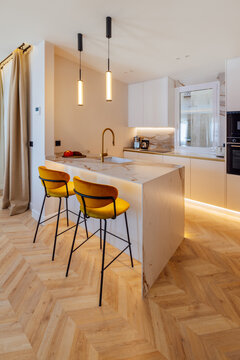 Modern kitchen interior with marble island and yellow stools