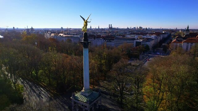 4K Aerial drone view of golden statue Nike of Paionios, angel symbol of piece, Friedensengel statue overlooking the city center Munich on a sunny warm autumn day by the river Isar