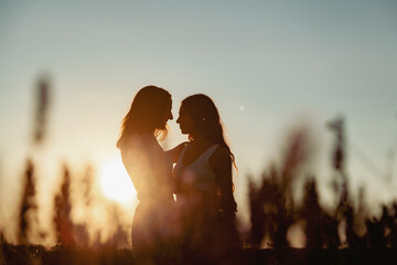 Romantic lesbian couple embracing in lavender field at sunset
