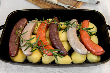 Close-up of bowl with raw homemade blood sausage, pork sausage and chorizo in oven with potatoes....
