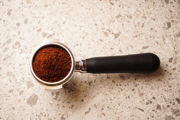 Freshly ground coffee in a holder for making traditional Italian espresso coffee. On a graphite table.