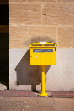 Yellow Postal Box on Stone Wall