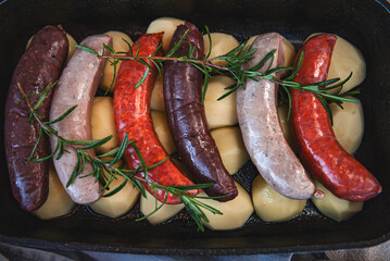 Close-up of bowl with raw homemade blood sausage, pork sausage and chorizo in oven with potatoes....