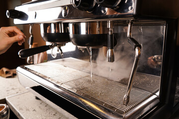 A barista works at the counter in a cafe, preparing to make coffee. Making coffee in a coffee shop.