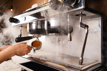 Close-up of hand Barista cafe making coffee with manual presses ground coffee using tamper at the coffee shop.