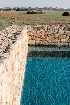 Rock walls surrounding a rustic pool in a traditional hotel in Puglia