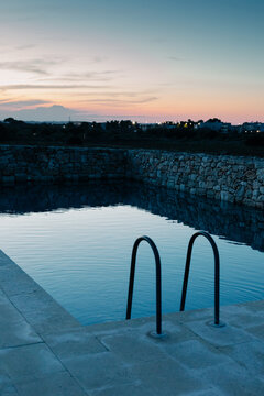 Pool in the yard of a hotel in Puglia with a sunset on the horizon
