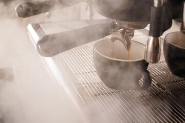 Professional espresso machine while preparing espressos coffee cup in a coffee shop. Close-up of espresso pouring from the coffee machine.