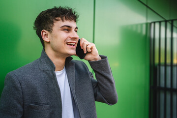 young handsome man talk on mobile phone on the green wall background