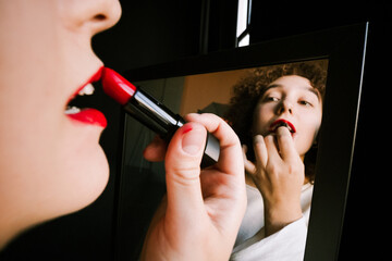 A girl paints her lips in front of the mirror