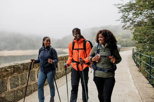 Three hikers walking and talking by a lake in autumn