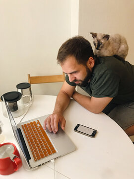 Man working wih cat sitting on his back