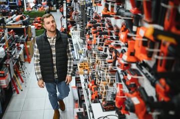 A man chooses a power tool in a hardware store