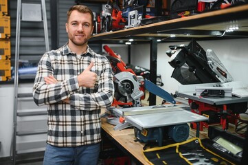 A male buyer chooses power tools in a hardware store. A large selection of tools