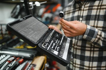 A man in a hardware store choosing a tool