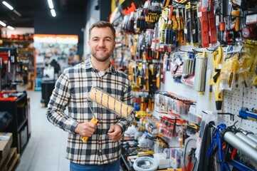 A male customer in a modern hardware store chooses a paint roller