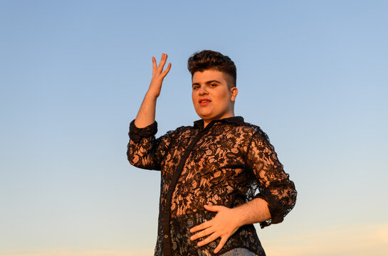 Positive non-binary person dancing against a clear sky