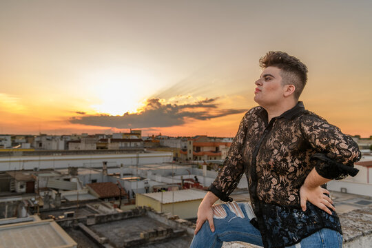 Pensitive non-binary person on the roof looking small town