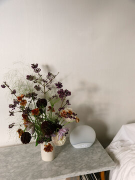 Floral arrangement and alarm clock on marble table