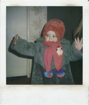 Young Child Wearing Winter Attire in Cozy Indoor Setting.Polaroid 1994