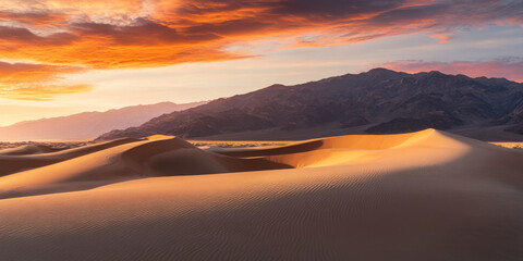 Obraz premium A dramatic desert landscape at sunset with towering sandstone formations, vibrant orange and pink skies, and long shadows cast across the dunes. The majestic and serene scene evokes awe.