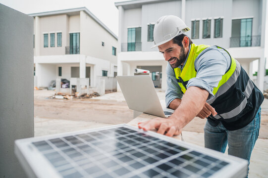 male engineer using laptop to inspect solar panels before installation at housing estate construction site